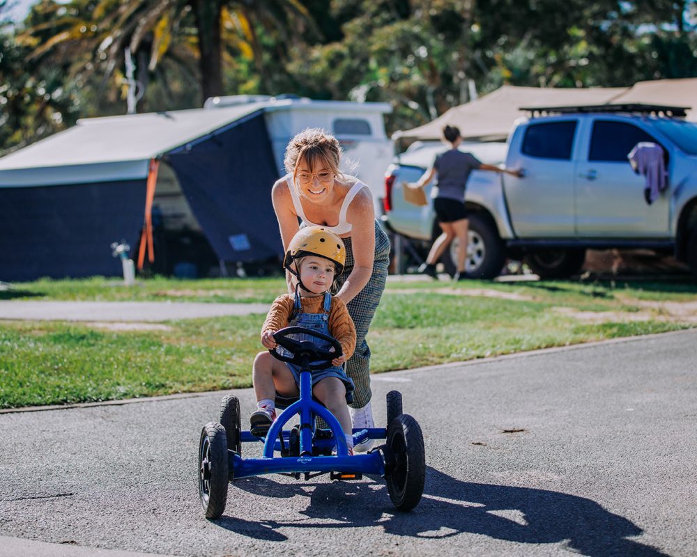 Burleigh Beach-kid riding on pedal cart