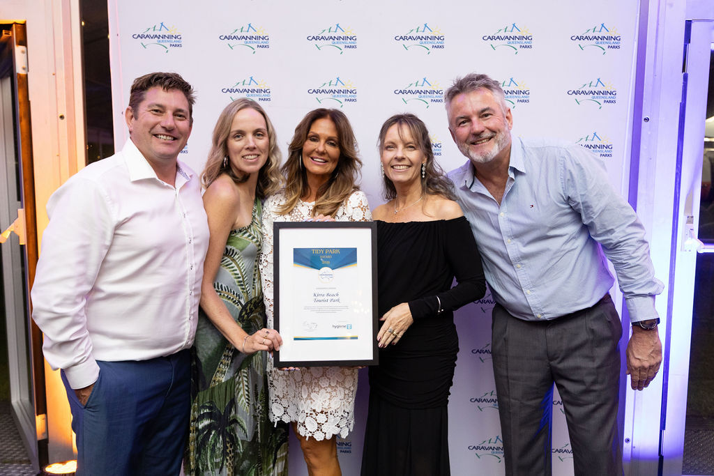 Kirra Beach Tourist Park staff members at the CPAQ awards night, smiling and holding their award plaque.