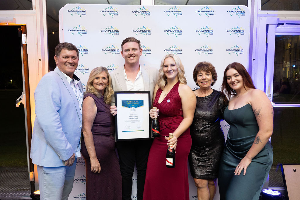 Broadwater Tourist Park staff members at the CPAQ awards night, smiling and holding their award plaque.
