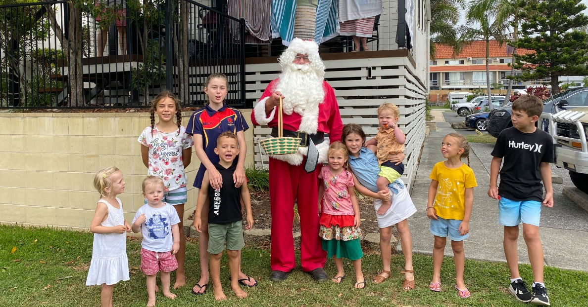 A group of children stand on the lawn with Santa