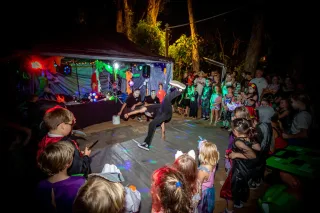 Performer break dancing infront of children dressed in halloween costumes