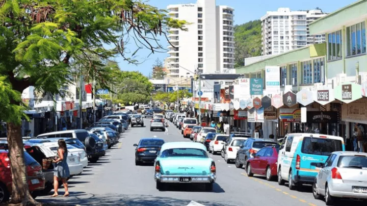Image of cars driving down James Street with people and parked cars along the sides.